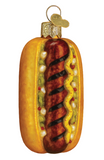 Hot dog ornament with mustard, relish, and a brown background