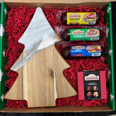 Box with Johnsonville sausages, a wooden cutting board, and a Christmas tree-shaped item on red crinkle paper.